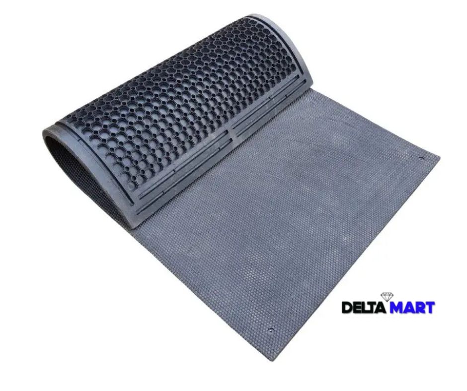 Roll-out rubber door mat with a textured perforated surface, partly rolled up