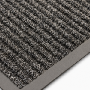 Close-up of a gray looped-pile doormat with a rubber edge, showing dense fiber texture.